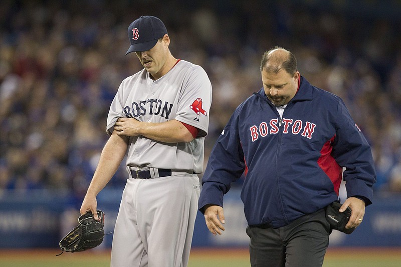 Boston Red Sox pitcher John Lackey, left, walks off the field with trainer Rick Jameyson after he was relieved in the fifth inning of a baseball game against the Toronto Blue Jays in Toronto on Saturday, April 6, 2013.