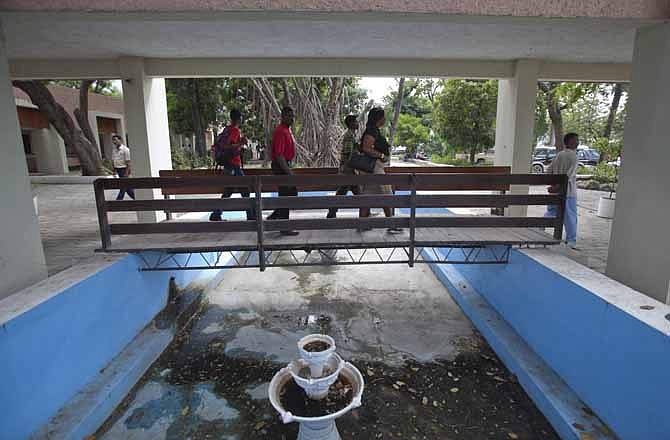 In this March 15, 2013 photo, people use a pedestrian bridge at the entrance at the country's main courthouse, which was renovated by Chemonics International Inc., a for-profit international development company based in Washington D.C., in downtown of Port-au-Prince, Haiti. A new report on American aid to Haiti in the wake of that country's devastating earthquake finds much of the money went to U.S.-based companies and organizations while just 1 percent went directly to Haitian companies. The findings confirm a long-term sense that U.S. foreign aid benefits more people at home than abroad as it takes a detour through Washington and its suburbs.