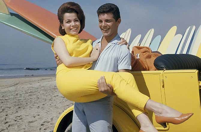 In this 1963 file photo, singer Frankie Avalon and actress Annette Funicello are seen on Malibu Beach during filming of "Beach Party," in California in 1963. Funicello helped create a world as fanciful as Walt Disney's Magic Kingdom when she traded in her Mousketeer ears for a modest one-piece bathing suit . It was a land of perfect waves and sparkling sand, in a place where there was a beach party every night and summer never ended.