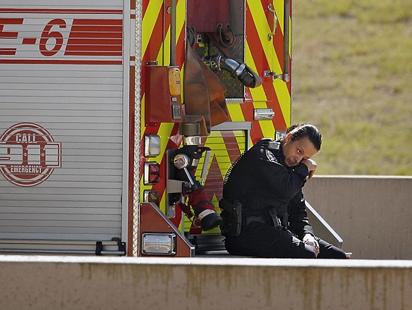
An Irving police officer wipes away tears after the last of the passengers from the Cardinal Coach Line charter bus were transported Thursday from the scene of a crash in Irving, Texas. At least two people were killed and more than 40 were hospitalized after the bus careened off a highway and flipped onto its side.