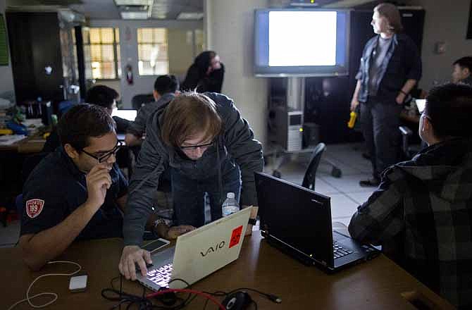 Julian Cohen, 22, center, a senior at the Polytechnic Institute of New York University (NYU-Poly) and a founder of the weekly Wednesday evening "Hack Night," works with fellow student Nitin Jami, left, as they start a prerecorded lecture (to be played on screen at right) in the darkened room of the Information Systems and Internet Security (ISIS) lab at the university Wednesday, April 10, 2013, in New York. The group of students are not getting together to learn how to hack computer data bases, rather they are studying to become cybersecurity experts to hopefully foil such attacks.