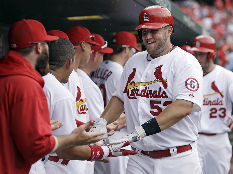 The Cardinals' Matt Adams is congratulated by teammates in the dugout after hitting a two-run home run during Wednesday's game against the Reds. Adams is hitting .643 so far this season.