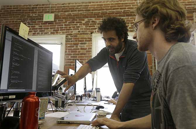 Shereef Bishay, co-founder of Dev Bootcamp, center, talks with student Ryan Guerrettaz during a class at Dev Bootcamp in San Francisco, Tuesday, April 2, 2013. Dev Bootcamp is one of a new breed of computer-programming schools that's proliferating in San Francisco and other U.S. tech hubs. These "hacker boot camps" promise to teach students how to write code in two or three months and help them get hired as web developers, with starting salaries between $80,000 and $100,000, often within days or weeks of graduation.