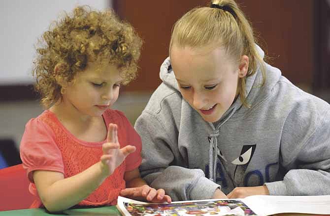 Meagan Engelbrecht, a sixth-grade student at Immanuel Lutheran School in Honey Creek, reads to a preschool student, Kendall Wood, 4, as part of their regular classtime activities. On a regular basis, the older students go to the younger students' room to read to them.