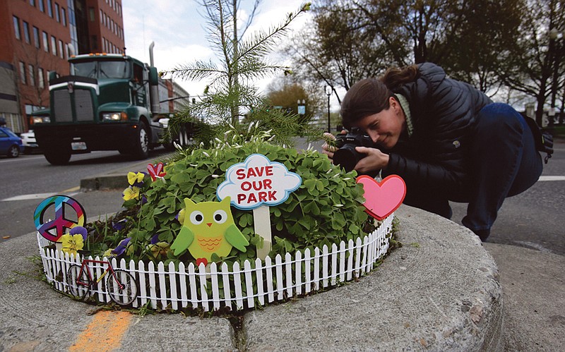 Allison Wildman crouches low to get a photo of Mill Ends Park in Portland, Ore., above. Tiny battle lines are being drawn in a whimsical British-American dispute over which country has the world's smallest park.