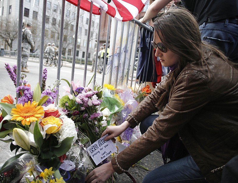 A mourner places a note with flowers at a police barricade Tuesday near the finish line of the Boston Marathon. The bombs that ripped through the crowd at the Boston Marathon, killing three people and wounding more than 170, were fashioned out of pressure cookers and packed with metal shards, nails and ball bearings to inflict maximum carnage, a person briefed on the investigation said Tuesday. 