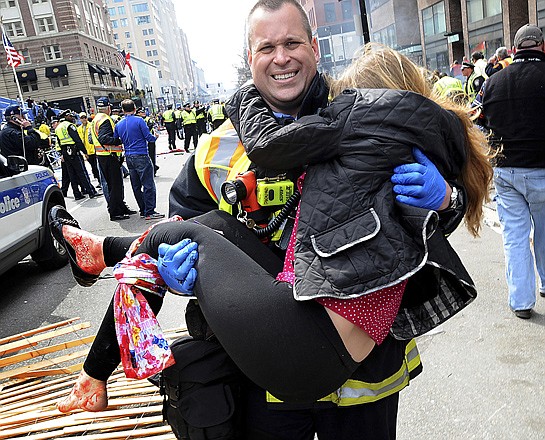 Boston firefighter James Plourde carries an injured girl away from the scene after Monday's bombing near the finish line of the Boston Marathon in Boston. Authorities say many injuries were from shrapnel.