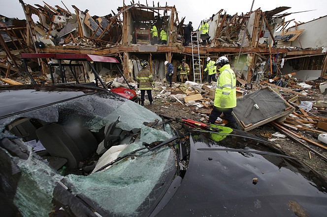 A smashed car sits Thursday in front of an apartment complex destroyed by an explosion Wednesday at a fertilizer plant in West, Texas, as firefighters conduct a search and rescue.