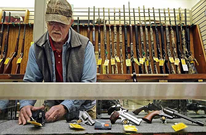 In this News Tribune file photo from January 21, 2013, Steve Sandy, a gun salesman at House of Bargains in Apache Flats, arranges handguns in the store's display case.