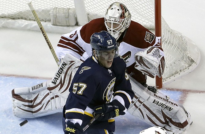 David Perron (57) of the Blues deflects the puck past Coyotes goalie Chad Johnson for a goal during the first period of Thursday's game in St. Louis. Looking on for Phoenix is Keith Yandle.