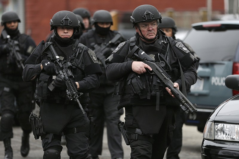 Police in tactical gear conduct a search for a suspect in the Boston Marathon bombings, Friday, April 19, 2013, in Watertown, Mass. 