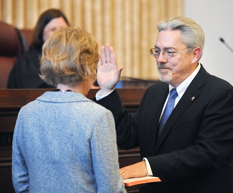 While his wife, Laura Wilson, holds the bible, the Honorable Paul C. Wilson repeats his oath of office as the newest member of the Missouri Supreme Court.