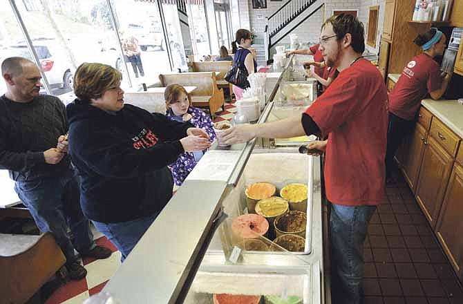 Tim Strope, right, hands a freshly scooped cup of ice cream to a customer while working the counter at the Central Dairy Ice Cream Shop in Jefferson City on Friday. 