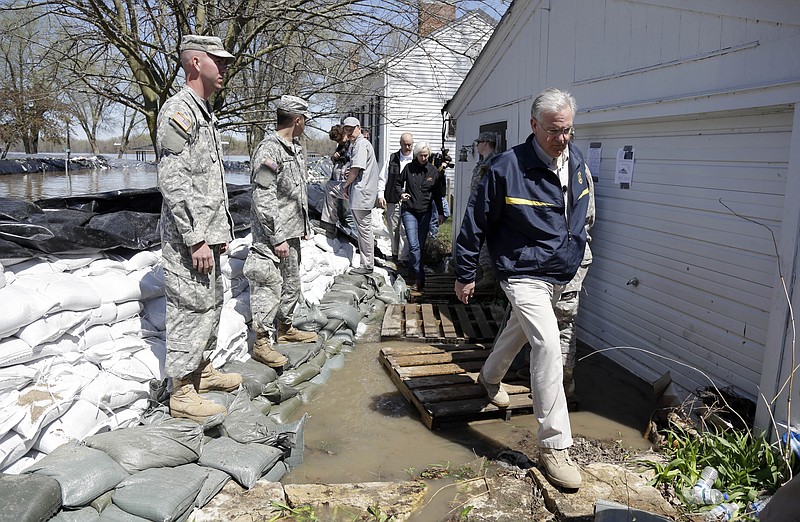 Gov. Jay Nixon, right, steps over a puddle after meeting with members of the Missouri National Guard as they made flood preparations on Saturday in Clarksville. Communities along the Mississippi River and other rain-engorged waterways are waging feverish bids to hold back floodwaters that may soon approach record levels. 
