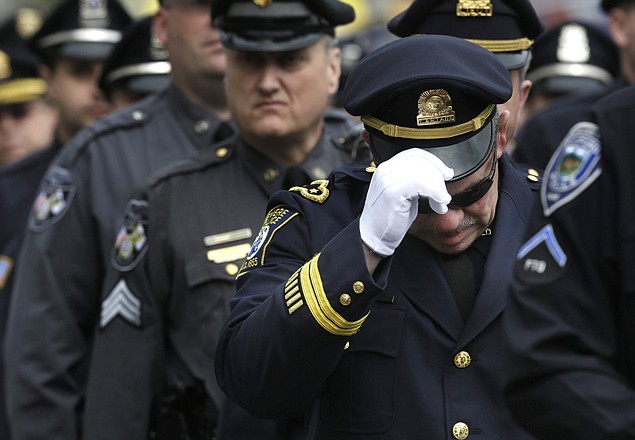 A Revere, Mass., police captain holds his cap Wednesday while entering a memorial service for fallen Massachusetts Institute of Technology police officer Sean Collier, in Cambridge, Mass.