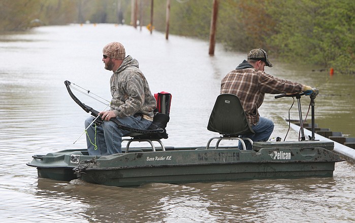 Kevin Eastman, left, prepares his bow for fishing Wednesday on the flooded Missouri Highway 94 just outside of West Alton as his brother, Sean Eastman, right, both of Ferguson, fights to keep the strong current from pressing their boat against the guardrail. The Mississippi River has flooded the highway.