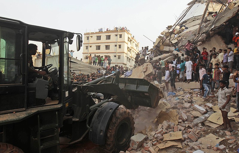 Bangladeshi soldiers use an earthmover during a rescue operation Wednesday at the site of a building that collapsed in Savar, near Dhaka, Bangladesh. An eight-story building housing several garment factories collapsed near Bangladesh's capital on Wednesday, killing dozens of people and trapping many more under a jumbled mess of concrete. Rescuers tried to cut through the debris with earthmovers, drilling machines and their bare hands.