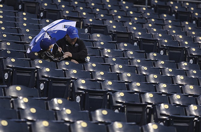 Two Royals fans take cover under an umbrella while waiting for the start of Friday's game between the Indians and Royals in Kansas City. The game was eventually postponed and will be made up as part of a doubleheader Sunday.