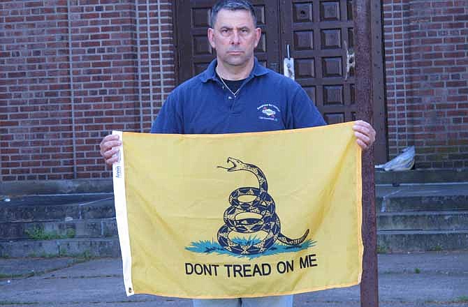 Peter Parente, president of the United Veterans Memorial and Patriotic Association, holds a Gadsden flag outside an armory in New Rochelle, N.Y., on Friday, April 26, 2013. The veterans group raised a Gadsden flag at the armory on March 21 but the city ordered it down because of its association with the tea party.