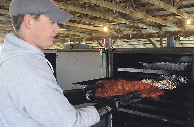 Doug Schaefer pulls a slab of ribs from a cooker as he and his cooking friend Dan Lewis (not pictured) participate for Hawthorn Bank in the Capital City Cook-Off in Jefferson City.