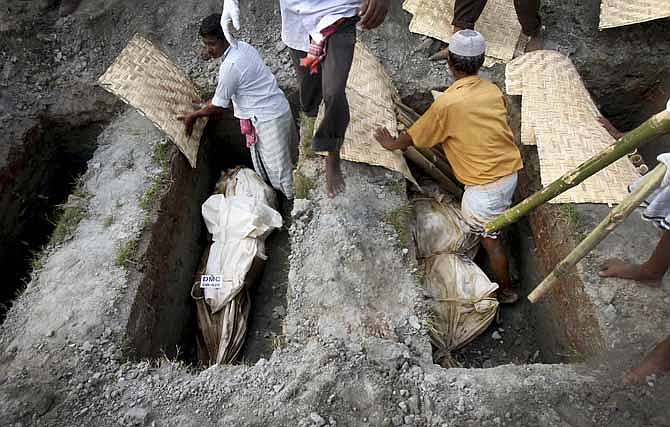 Workers bury unclaimed bodies from the garment factory building collapse Wednesday in preparation for a mass burial in Dhaka, Bangladesh. Several hundred people attended a mass funeral in a Dhaka suburb for 18 unidentified workers who died in the building collapse last week in the country's worst industrial disaster, killing at least 402 people and injuring 2,500.