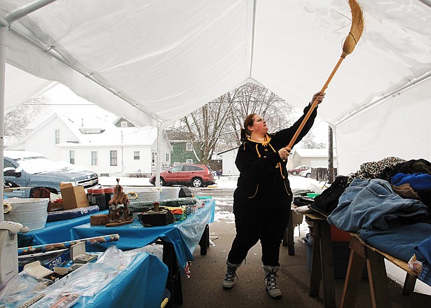 Elizabeth Holubar pushes snow off the top of a tent over her garage sale Thursday in Winona, Minn. Elizabeth and her mother are set to participate in the annual 100-mile garage sale in Minnesota. 