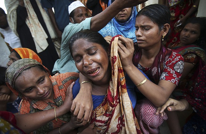 A woman is comforted by family members and others on Friday after she identified the decomposed body of her husband, which was recovered from the rubble of a garment factory building that collapsed last week in Savar, near Dhaka, Bangladesh.