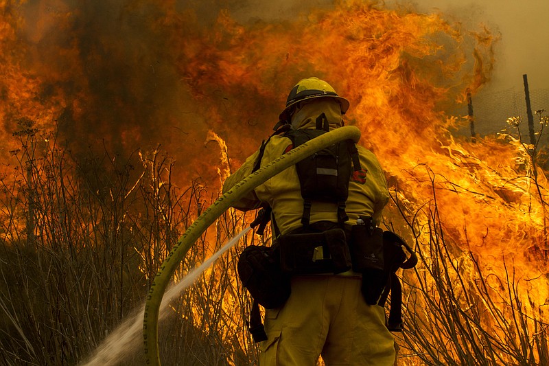 A firefighter battles the wildfire Friday near the farmland along a hillside in Point Mugu, Calif. A huge wildfire carved a path to the sea and burned on the beach Friday, but firefighters got a break as gusty winds turned into breezes. Temperatures remained high, but humidity levels were expected to soar as cool air moved in from the ocean and the Santa Ana winds retreated.