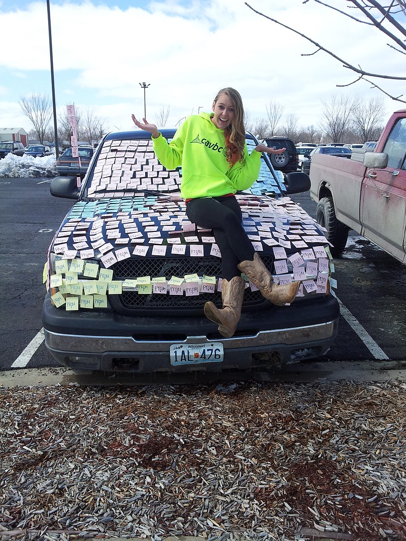 Jefferson City High School junior Madison Bond sits on her boyfriend's truck after placing 1,300 Post-It notes on it.