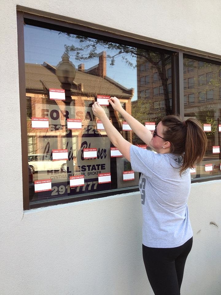 Sara Amick places a sticker on the window of a vacant downtown storefront.