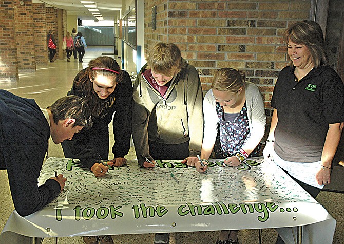 Brock Raffaele of Cadillac, Mich. and Sault High students Lauren Gee, Conner Langendorf, and Emma Harrington, take the KDR Challenge not to drive while distracted, and sign the banner as speaker Bonnie Raffaele, right, watches in Sault Ste. Marie, Mich. 