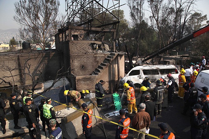 Firefighters work next to destroyed houses and vehicles after a gas tanker truck exploded on a nearby highway in the Mexico City suburb of Ecatepec early Tuesday. The blast killed and injured dozens, according to the Citizen Safety Department of Mexico State. Officials did not rule out the possibility the death toll could rise as emergency workers continued sifting through the charred remains of vehicles and homes built near the highway on the northern edge of the metropolis.