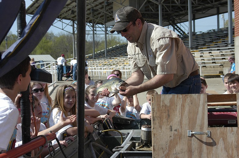Scott Williams, Missouri Department of Conservation fisheries biologist, shows a largemouth bass to the fifth and sixth grade students assembled at Student Conservation Day at the fairgrounds. 
