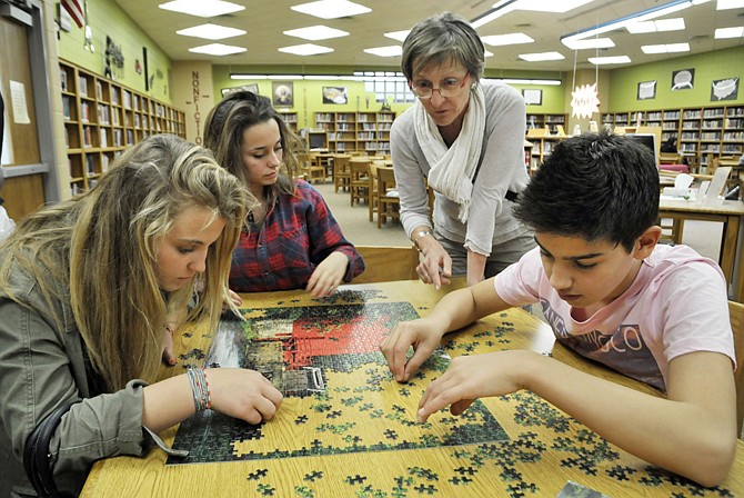 Thirty students, along with three teachers from Leone, France, are visiting Jefferson City and Thomas Jefferson Middle School and have been since April 24. Here, from left, Capucine Broussaudier, Margot Granger and Pacome Chazelle work under the helpful guidance of teacher, Pascale Dassin, standing, to put together a puzzle of the mill at Alley Springs.