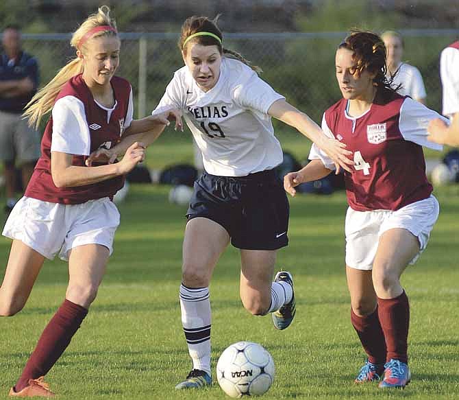 Becky Roberts of Helias drives her way between Rolla's London Clift (left) and Amy Jernigan during Tuesday's game at the 179 Soccer Park.