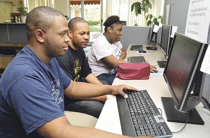 Antony Gregory, middle, helps freshman students Harvey McClinton and DuKychia Hagan as they check grades at the end of this school year. Gregory is set to graduate from Lincoln University if he can pay off the nearly $500 he owes the school.