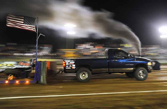 Leah Scott of California, Mo., hits the throttle on her diesel-powered Dodge "Executioner" and powers the sled down the fairgrounds track during the Jefferson City Jaycees "Pulling For Camp" truck and tractor pull on Saturday night. 