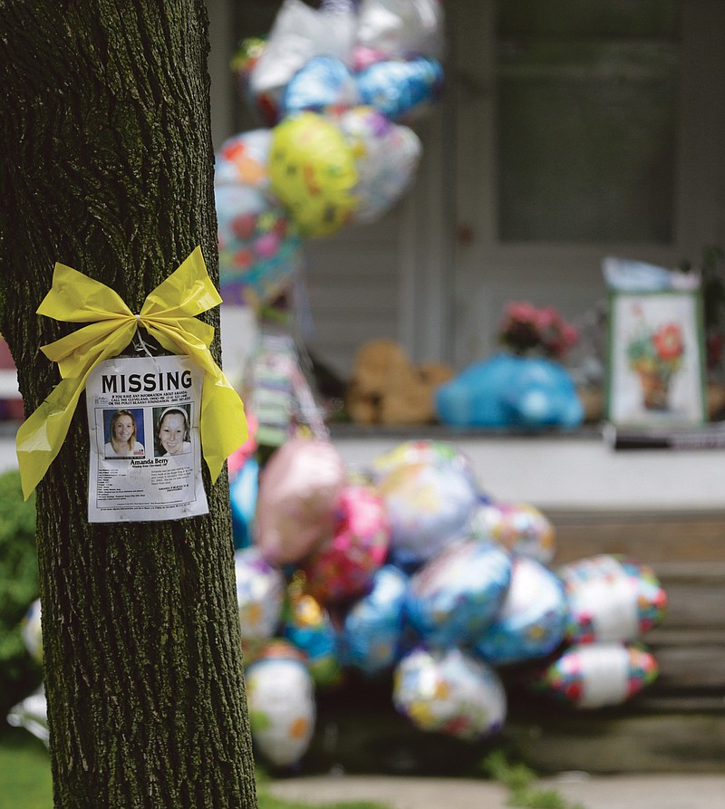 A missing poster still hangs on a tree at the home where Amanda Berry was staying in Cleveland on Saturday.