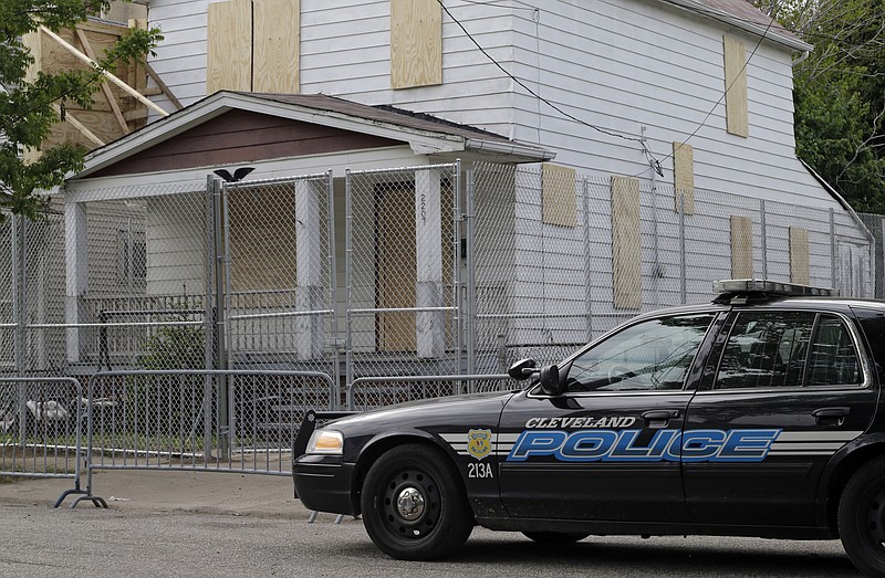 A Cleveland police patrol car sits Tuesday in front of the boarded up home of Ariel Castro in Cleveland. Three women were rescued from the house last week after a decade in captivity. Castro is under arrest and charged with rape and kidnapping.