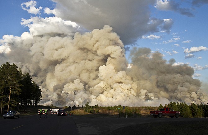 A smoke plume rises high above a road block Tuesday east of Solon Springs, Wis. Investigators say the fire cased by logging operations wasn't intentionally set.