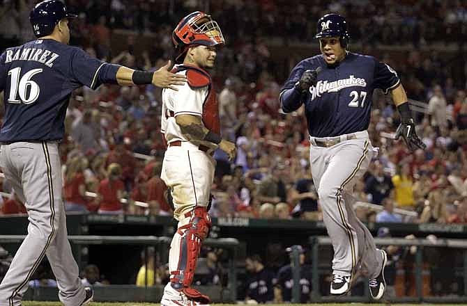 Milwaukee Brewers' Carlos Gomez, right, is congratulated by Aramis Ramirez, left, as he scores past St. Louis Cardinals catcher Yadier Molina on a two-run single by Jeff Bianchi during the 10th inning of a baseball game Saturday, May 18, 2013, in St. Louis. The Brewers won 6-4.