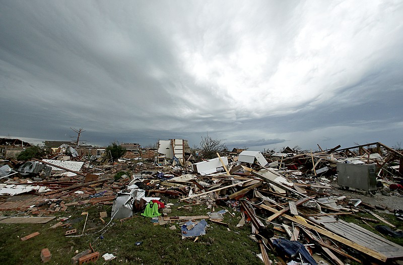 Storm clouds build in the distance beyond tornado-ravaged homes Tuesday in Moore, Okla. A huge tornado roared through the Oklahoma City suburb Monday, flattening entire neighborhoods and destroying an elementary school with a direct blow as children and teachers huddled against winds.