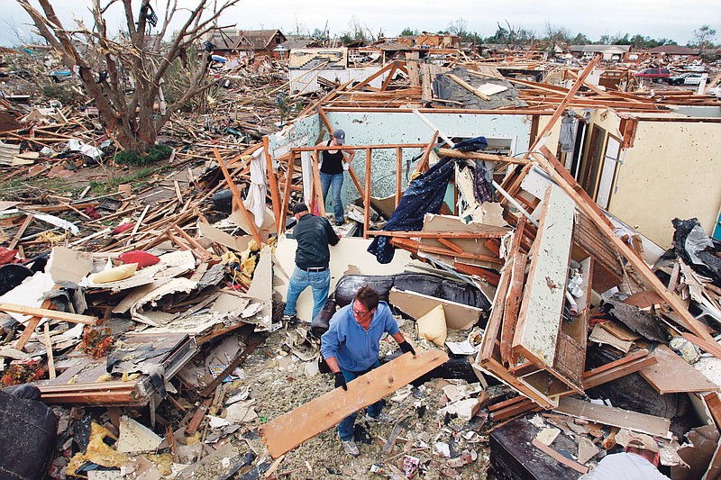 Jimmy Hodges helps Chad Heltcel and his wife Cassidi salvage the wreckage of Chad Heltcel's family home, which was destroyed Monday when a tornado moved through Moore, Okla., Tuesday, May 21, 2013.