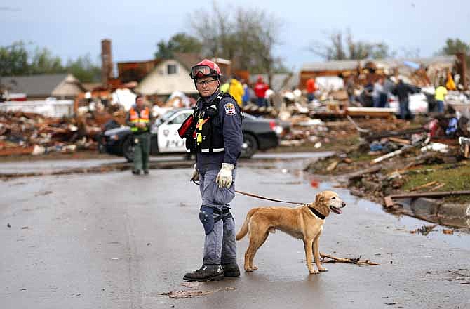 A rescuer searches a neighborhood near Telephone Road on Tuesday, May 21, 2013, in Moore, Okla., where a mammoth tornado destroyed countless homes, cleared lots down to bare red earth and claimed 24 lives. 