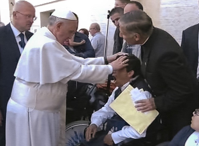 Pope Francis lays his hands on the head of a young man on Sunday after celebrating Mass in St. Peter's Square. The young man heaved deeply a half-dozen times, convulsed and shook, and then slumped in his wheelchair as Francis prayed over him.