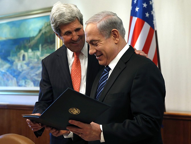 U.S. Secretary of State John Kerry, left, gives a present to Israeli Prime Minster Benjamin Netanyahu in Jerusalem on Thursday. The United States and Israel are raising hopes for a restart of the Middle East peace process after more than four years of hardly any talks. 