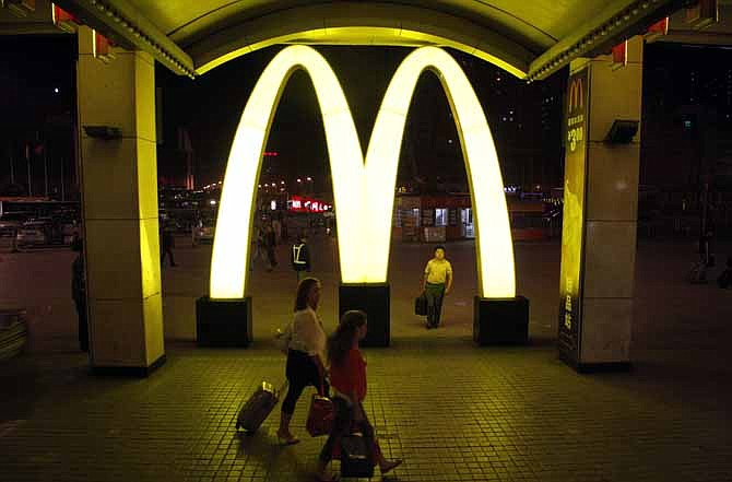 In this May 2011 file photo, passengers walk near a large sign for the fastfood chain McDonald's at the train station in northern China. After years of outperforming its rivals, the company has been struggling to increase sales more recently.