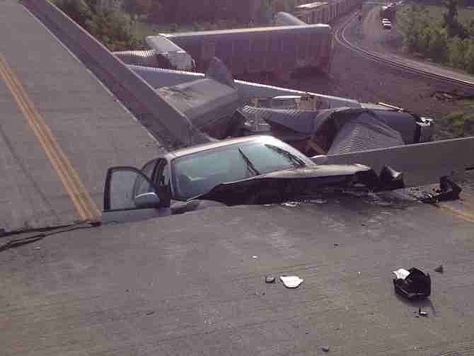 A car lies in-between damaged sections of a highway overpass near Rockview, Mo. on Saturday, May 25, 2013. Authorities said the roadway collapsed when rail cars slammed into one of the bridge's pillars after a cargo train collision. Seven people were injured, though none seriously. 