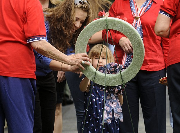 Melanie Moore helps her daughter Abigail place a poppy in the memorial wreath in honor of father and grandfather, Ben Goodin, during the Two Bell Ceremony portion of Monday's Memorial Day program at the Jefferson City National Cemetery. The Moore family traveled from Dallas to visit family and honor Goodin, a veteran of both the Navy and National Guard, who died earlier this year. Top, a poppy is readied for placement on the wreath.
