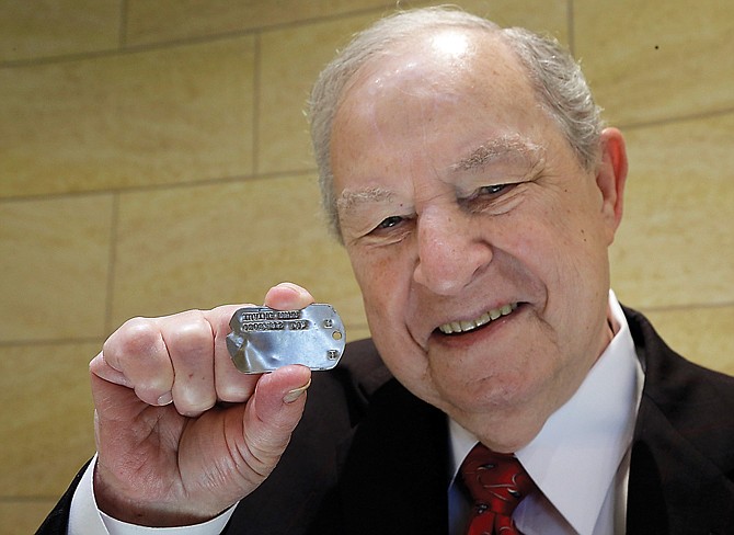 World War II veteran Irving Mann poses for a photo with his dog tag that was found and returned to him, in Rochester, N.Y. Mann says he was skeptical when an email from a French woman recently arrived at his Rochester jewelry store. She said she'd found the tag in her barley field and was looking for its owner.